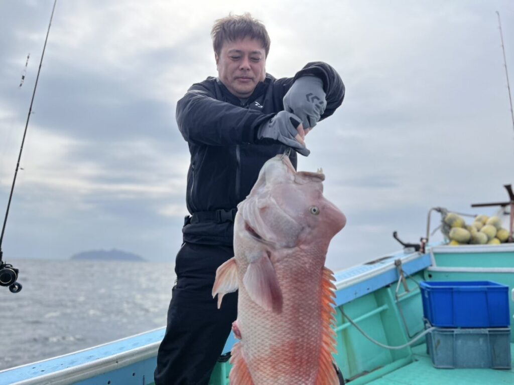 ボートのデッキに立っている人物が、大きな魚を抱えています。