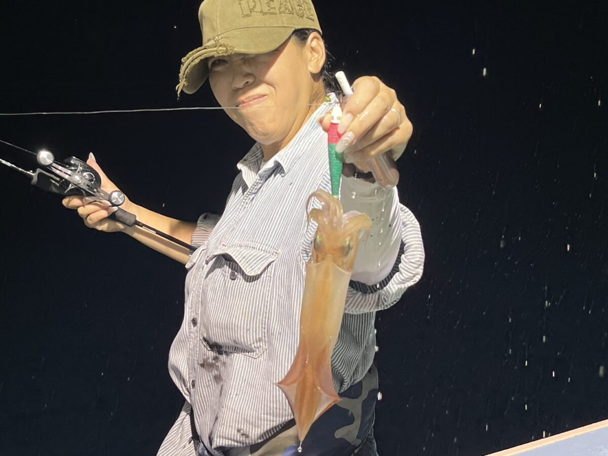 釣り上げたケンサキイカを手に笑顔を見せる釣り人