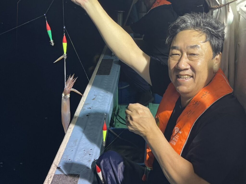 スッテに掛けたケンサキイカを見せる釣り客。若潮丸の夜焚きイカ釣り