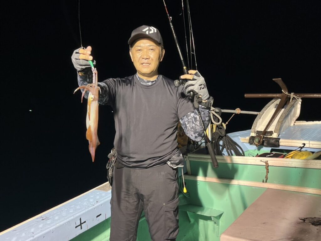 手にしたケンサキイカを掲げる釣り客。玄界灘・宗像大島沖の夜焚きイカ釣り