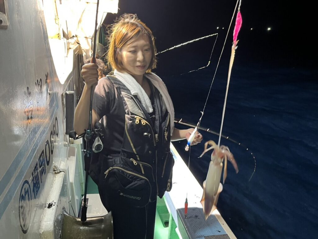 仕掛けに掛かったケンサキイカを見つめる釣り客。若潮丸の夜焚きイカ釣り