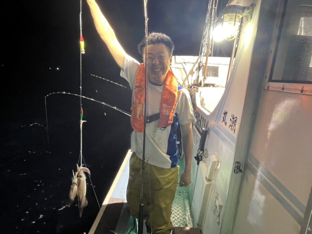釣れたケンサキイカを掲げて喜ぶ釣り客。若潮丸の夜焚きイカ釣り