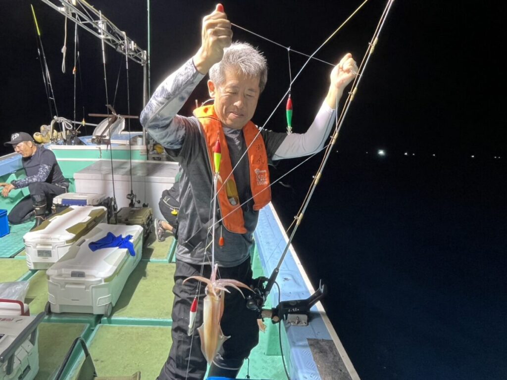 釣り上げたケンサキイカを掲げる釣り客。若潮丸の夜焚きイカ釣り