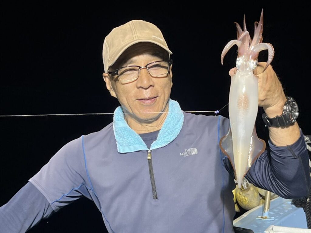 スッテに掛けたケンサキイカを掲げる釣り客。若潮丸の夜焚きイカ釣り