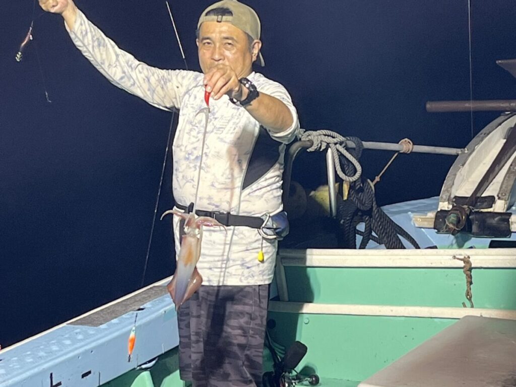 スッテに掛けたケンサキイカを掲げる釣り客。若潮丸の夜焚きイカ釣り