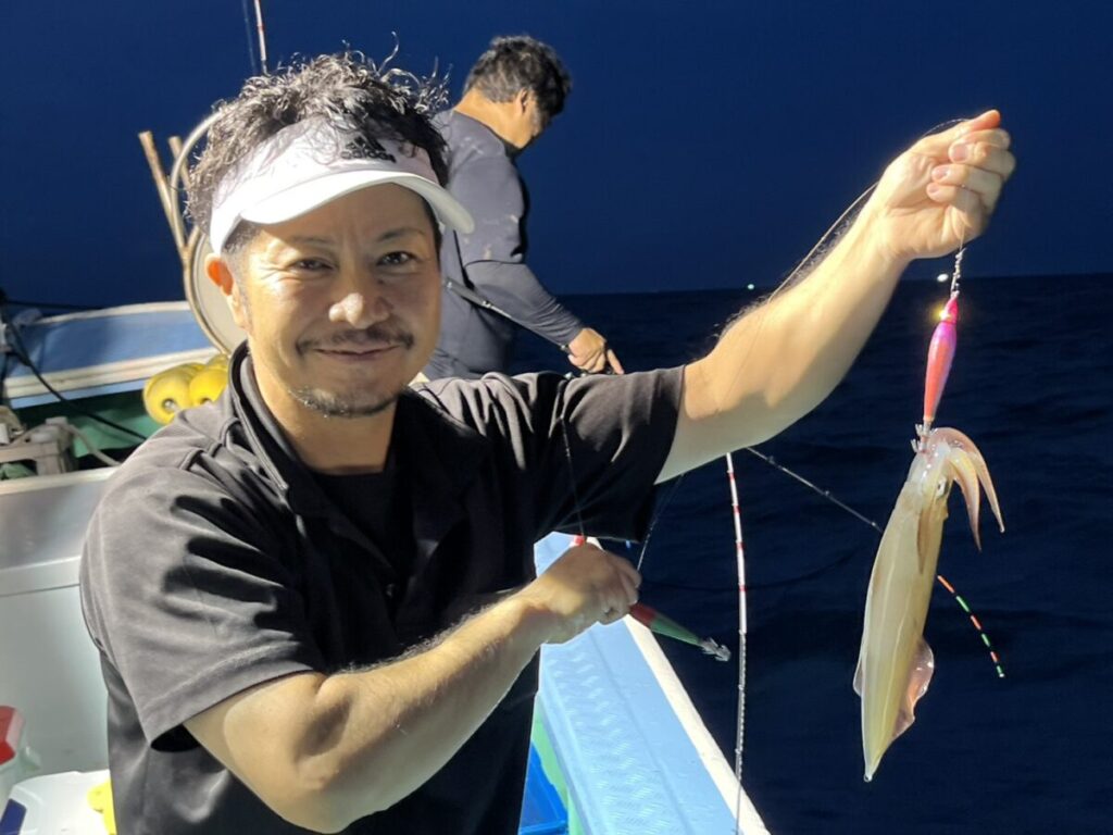 スッテに掛けたケンサキイカを掲げる釣り客。若潮丸の夜焚きイカ釣り