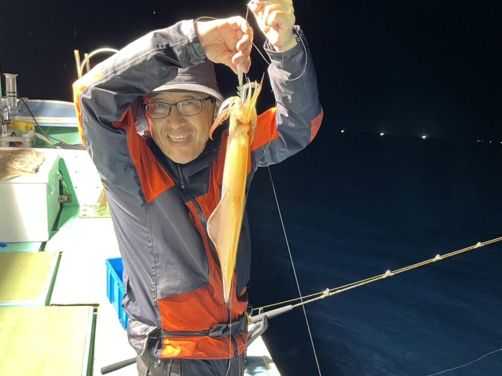 スッテに掛けたケンサキイカを掲げる釣り客。若潮丸の夜焚きイカ釣り