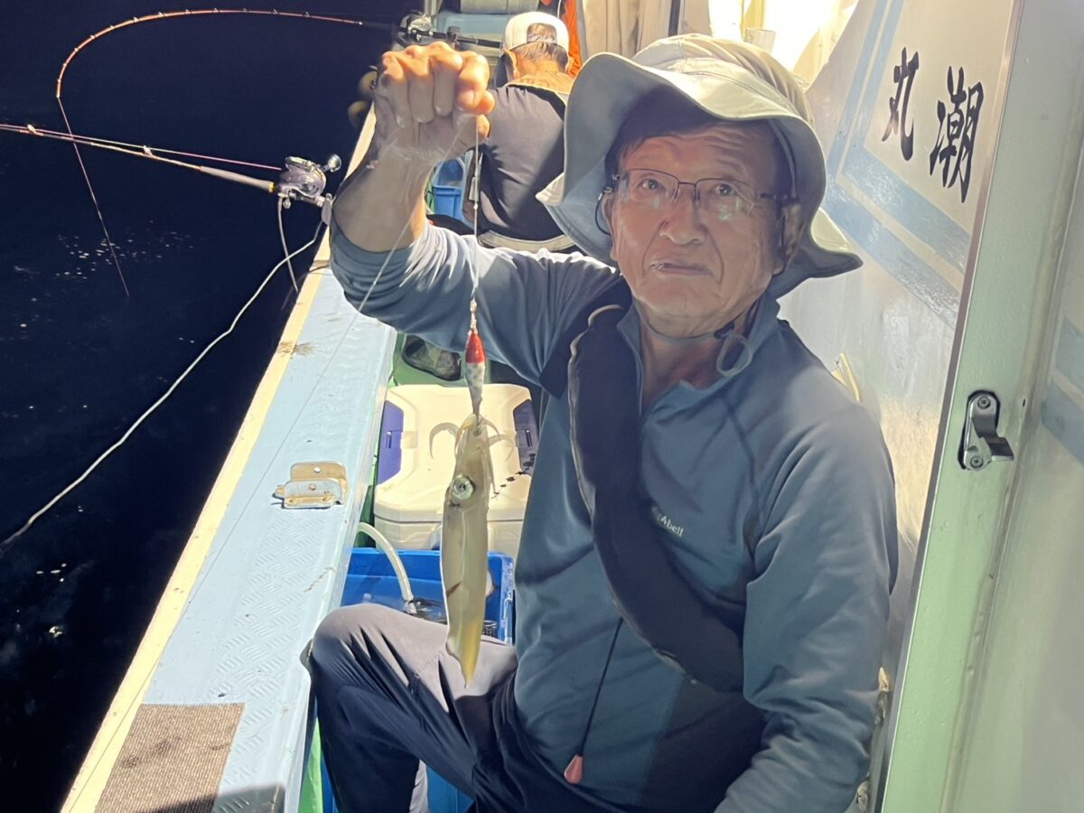 スッテに掛けたケンサキイカを掲げる釣り客。若潮丸の夜焚きイカ釣り