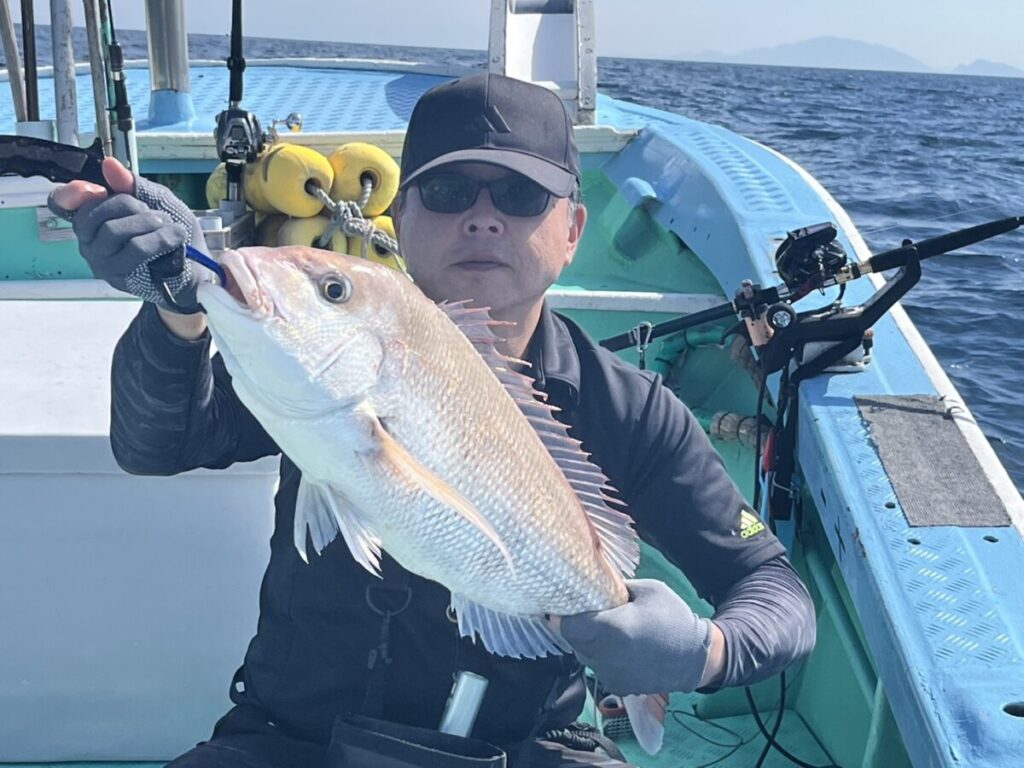 釣り上げたタイを手にする釣り客。若潮丸の落とし込み釣り